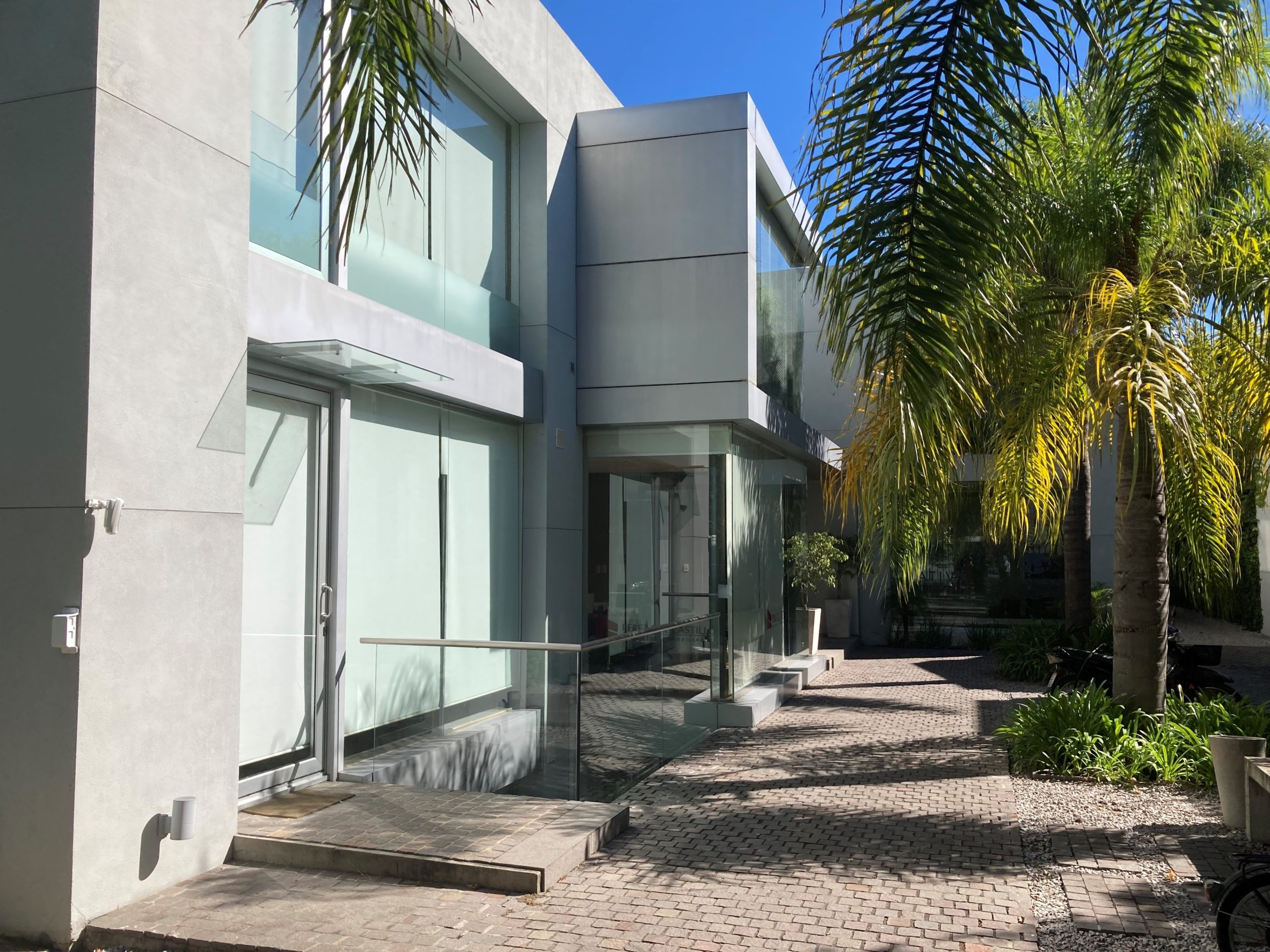 Modern building with glass entrance and palm trees.